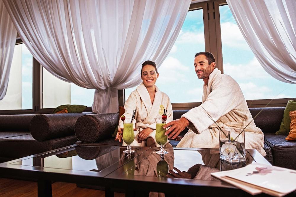 Grand Hotel Bernardin Portorose Esterno foto The photo features a relaxed setting where a man and a woman are sitting together in a stylish lounge area. Both are wearing plush robes, indicating they might be enjoying a spa day or a similar leisure experience. They seem to be smiling and enjoyin