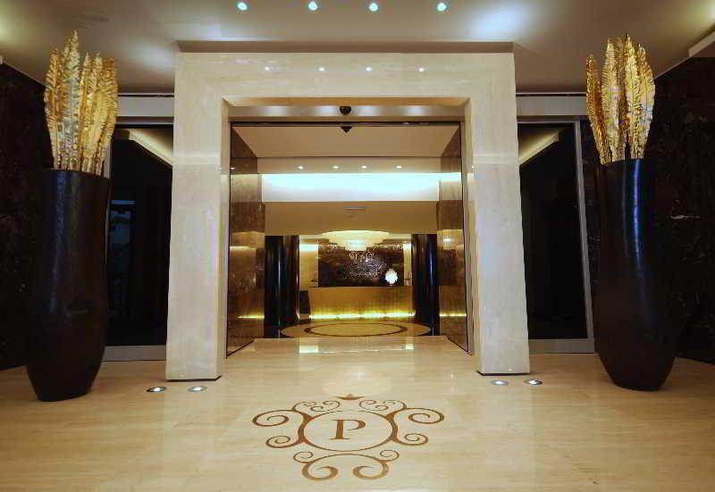 Grand Hotel Bernardin Portorose Esterno foto The photo shows an elegant entrance to a lobby. There is a large, ornate archway made of light-colored stone, leading into a well-lit area. On either side of the entrance, there are tall, dark vases that contain decorative golden elements resembling 