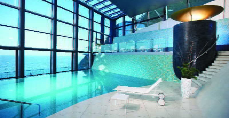 Grand Hotel Bernardin Portorose Esterno foto The image showcases a luxurious indoor pool area. The pool features a clear, turquoise water and is surrounded by large glass windows, allowing natural light to flood the space and offering a scenic view. The walls have a modern design, with one side