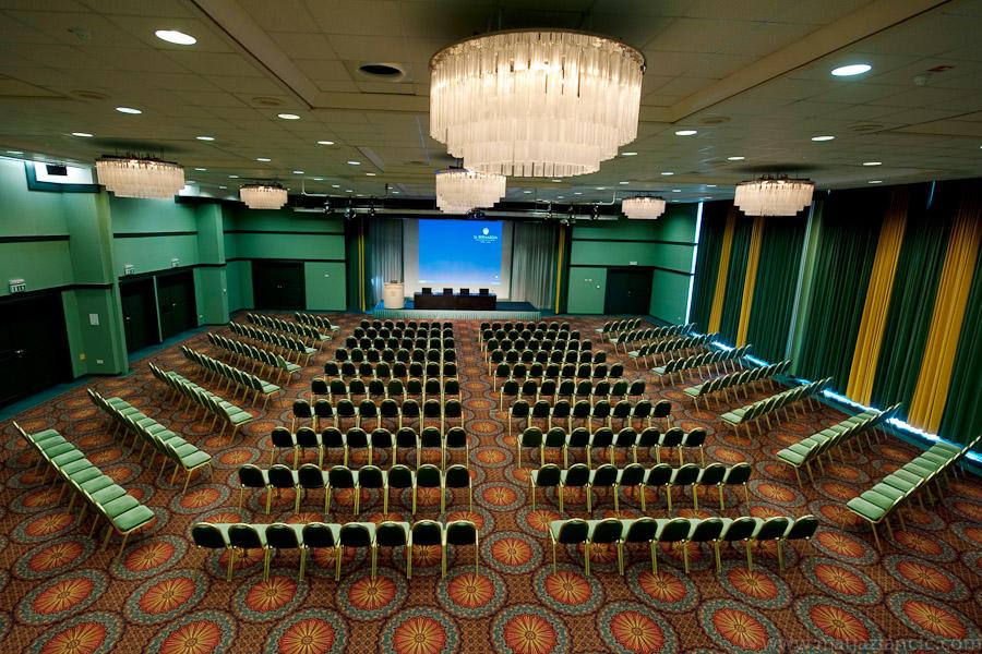Grand Hotel Bernardin Portorose Esterno foto The photo showcases a large conference room set up for an event. There are multiple rows of chairs arranged in a grid pattern, all facing a stage or presentation area at the front. The room is well-lit with chandeliers hanging from the ceiling, and t