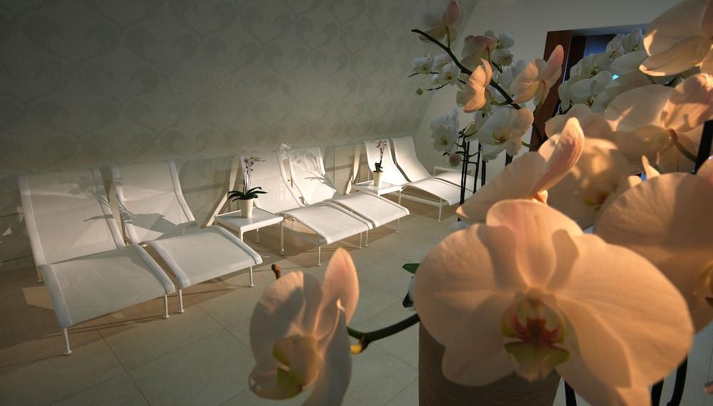 Grand Hotel Bernardin Portorose Esterno foto The photo shows a serene indoor space designed for relaxation. In the foreground, there are beautiful orchid flowers, adding a touch of elegance. In the background, several white lounge chairs are arranged in a row, suggesting a spa or relaxation are