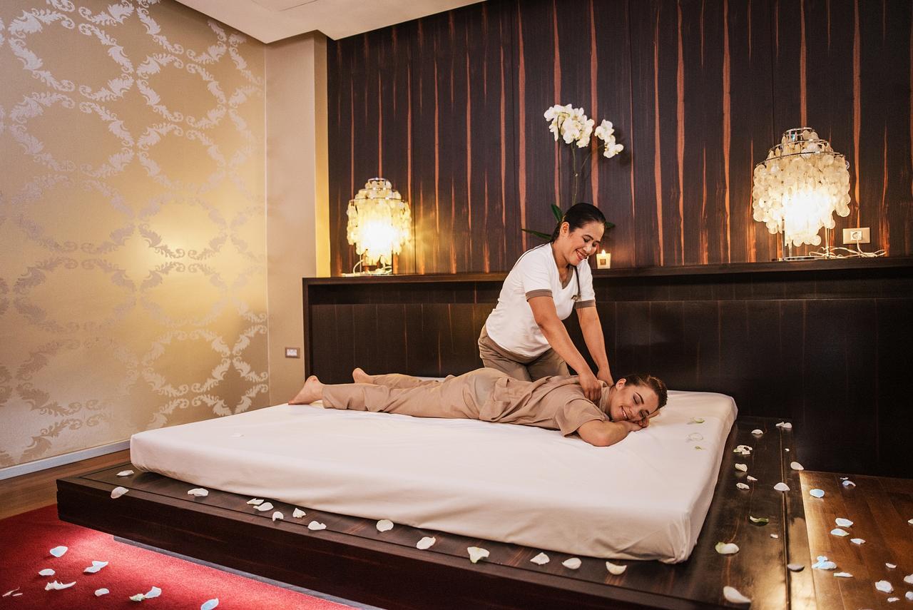 Grand Hotel Bernardin Portorose Esterno foto The photo shows a relaxing spa setting where a massage therapist is performing a back massage on a client. The client is lying on a massage table, covered with a sheet and wearing a comfortable outfit. The room has a soothing ambiance, with warm ligh