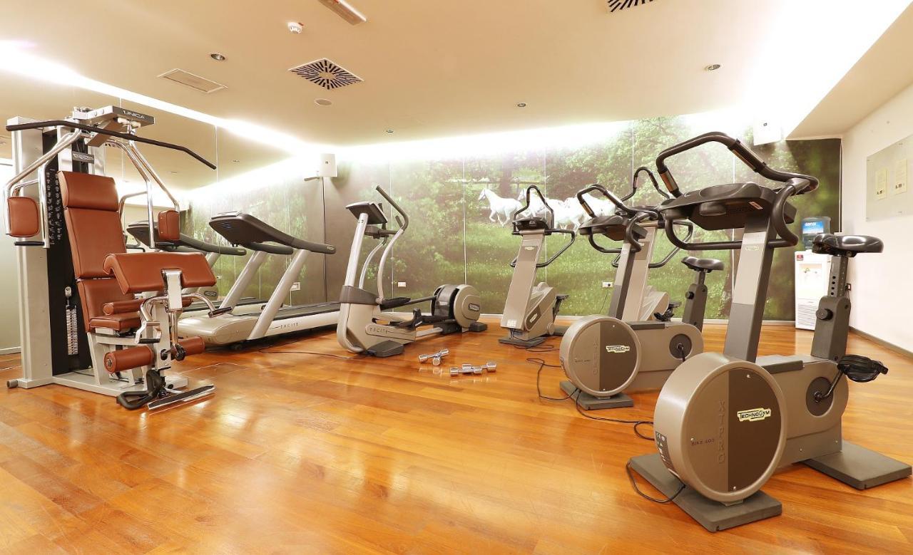Grand Hotel Bernardin Portorose Esterno foto The photo shows a fitness room equipped with various exercise machines. There are cardio machines such as stationary bikes and elliptical trainers, as well as strength training equipment, specifically a multi-station machine. The flooring appears to 